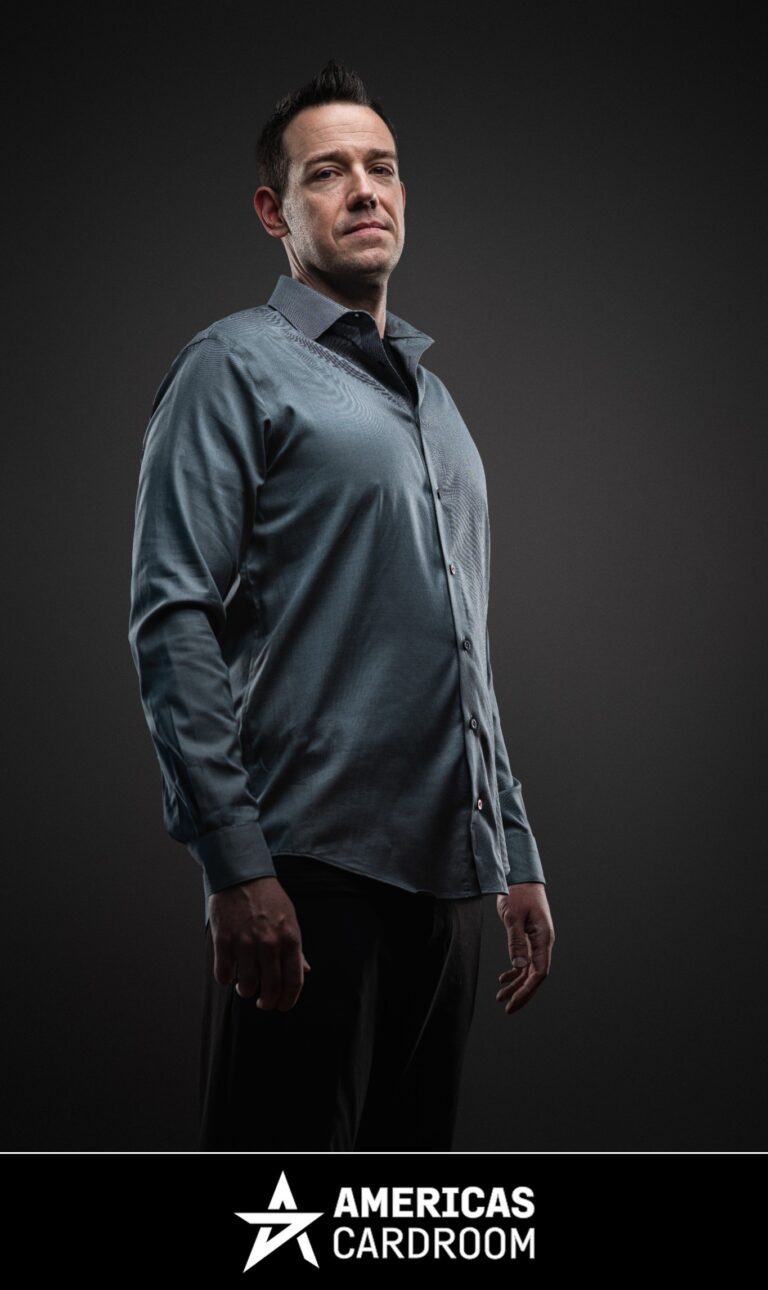 A medium shot of Jeff Boski, an ACR poker pro, looking directly at the camera with a serious expression. He is wearing a long-sleeved grey button-up shirt and black pants, against a dark background.