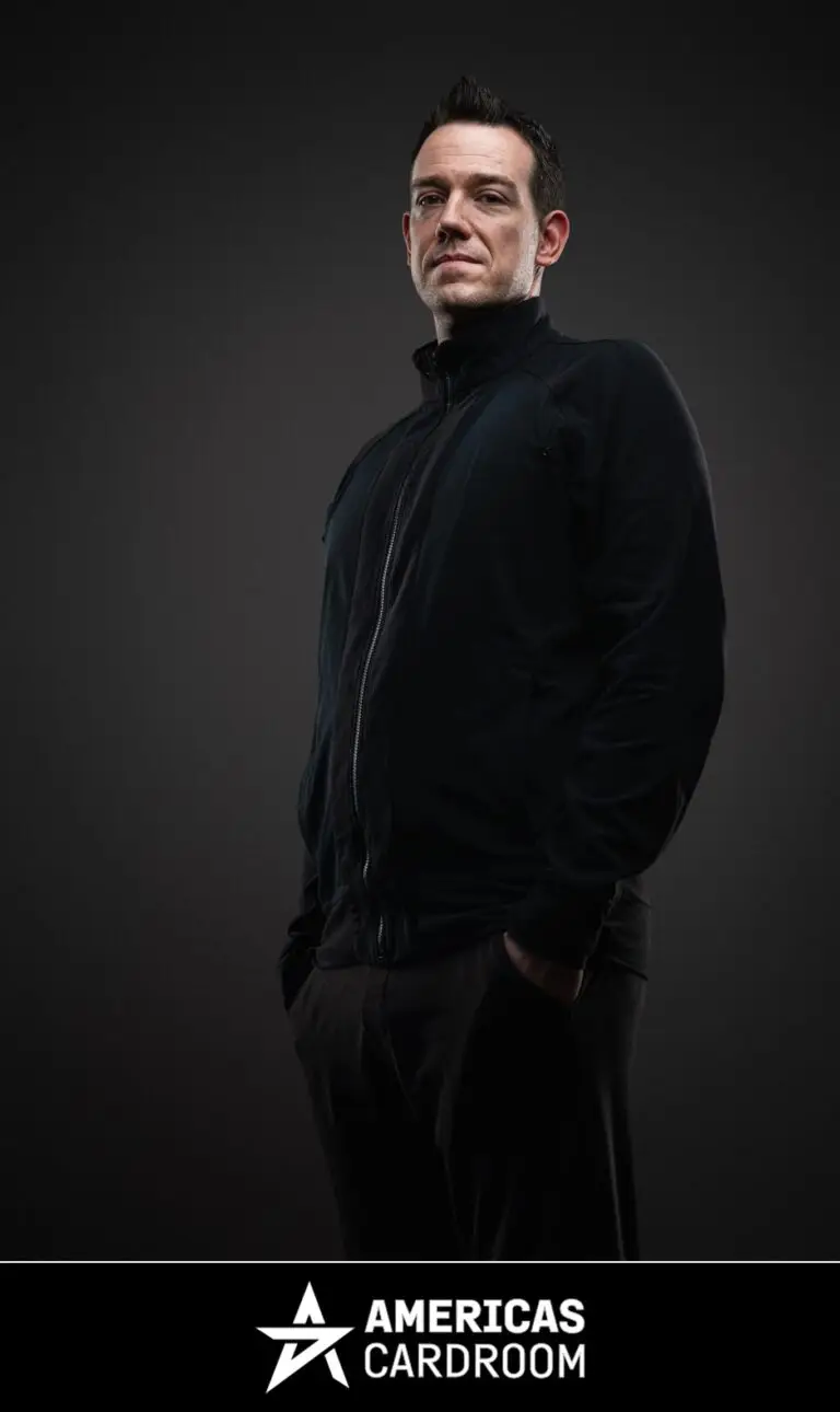 A medium shot of Jeff Boski, an ACR poker pro, looking directly at the camera with a serious expression. He is wearing a black zip-up jacket and black pants, with his hands in his pockets, against a dark background.